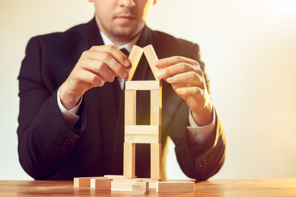 Man and wooden cubes on table. Management concept Building Home